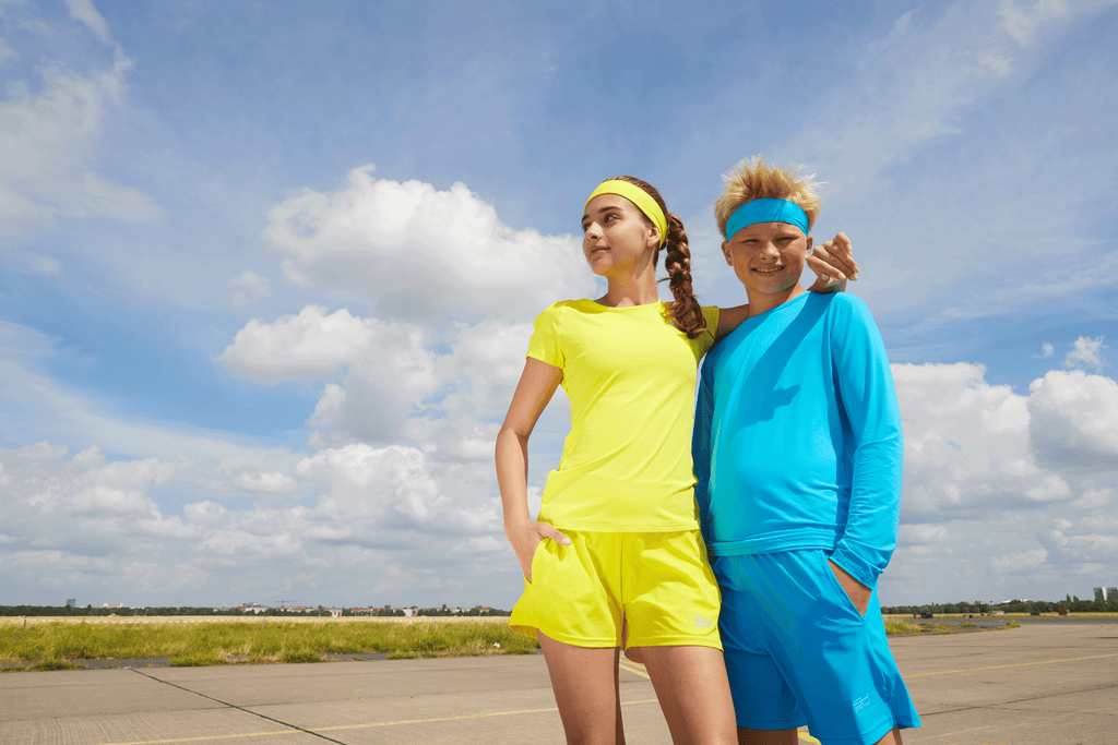 Mädchen mit gelber und Junge mit blauer Sportkind Tenniskleidung